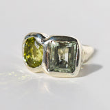 Silver ring with two green gemstones on a light gray background