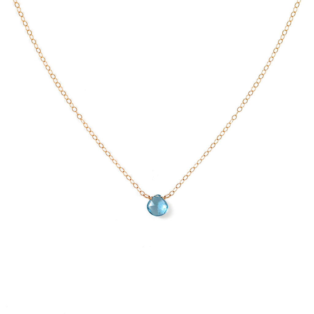 london blue topaz gemstone and dainty gold chain necklace against white background