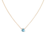 london blue topaz gemstone and dainty gold chain necklace against white background