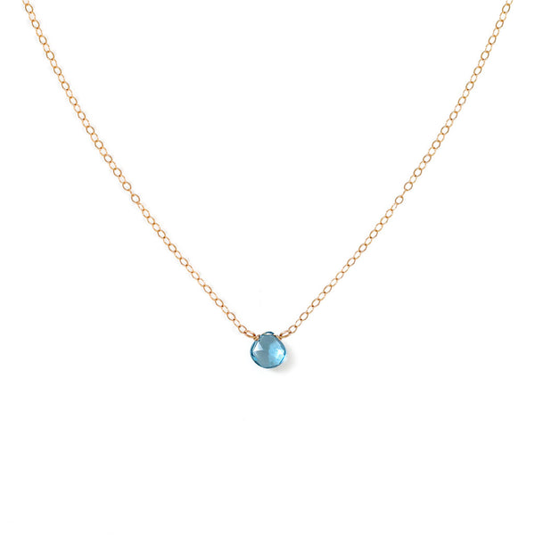 london blue topaz gemstone and dainty gold chain necklace against white background