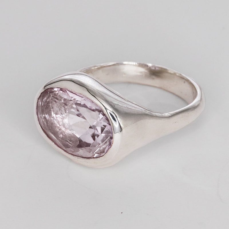 Silver ring with a pink gemstone on a light gray background