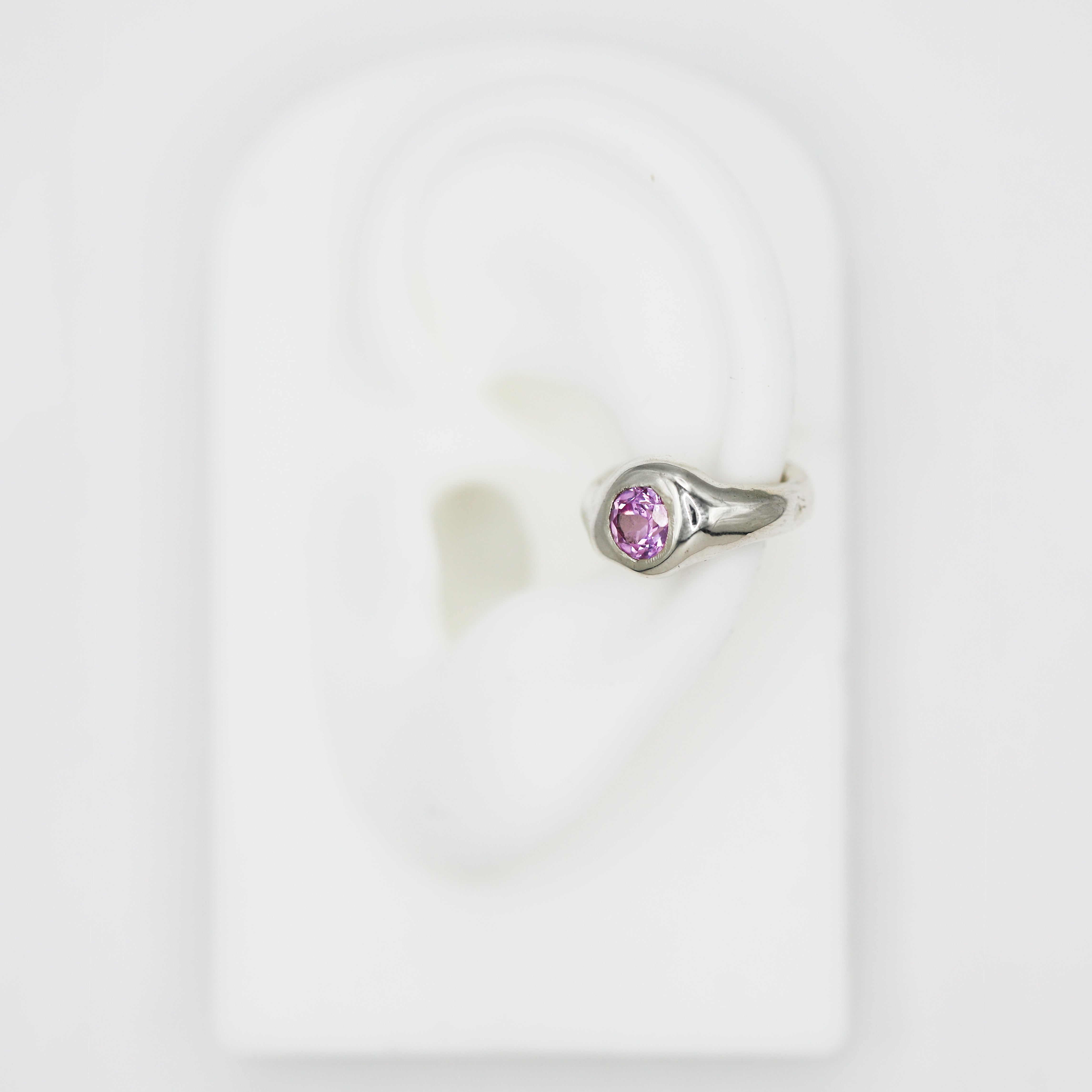 silver ear cuff with pink sapphire gemstone on fake ear