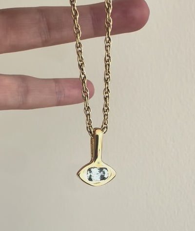 video of a gold eye-shaped pendant with blue montana sapphire on gold rope chain held by a hand