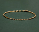 gold rope chain bracelet on green background