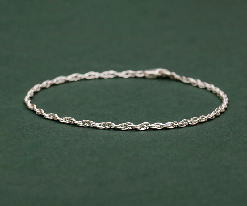 silver rope chain bracelet on green background