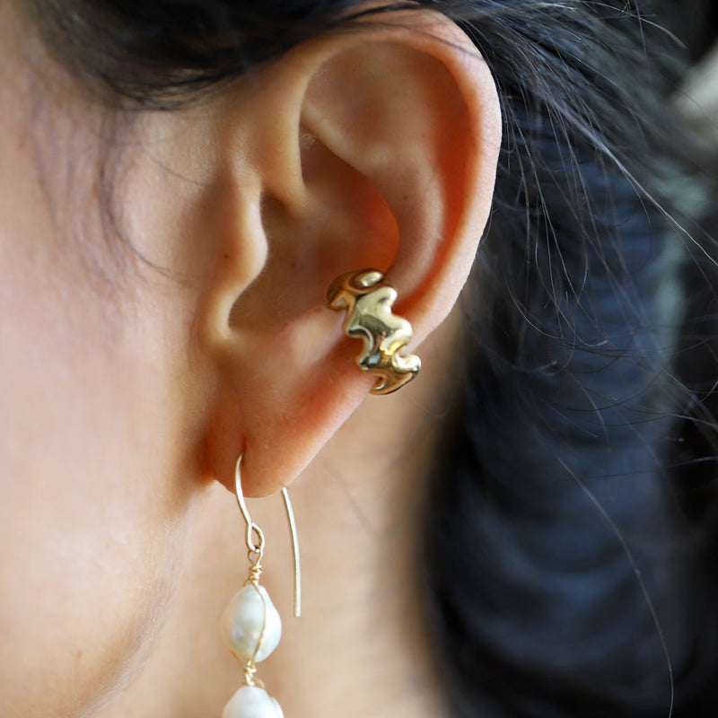 closeup of ear with wavy cartilage ear cuff in gold