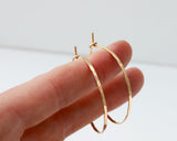 small gold endless hoop earrings on fingers to show scale