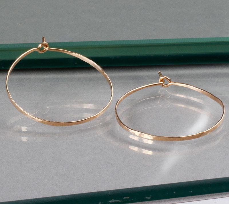small gold endless hoop earrings on green glass