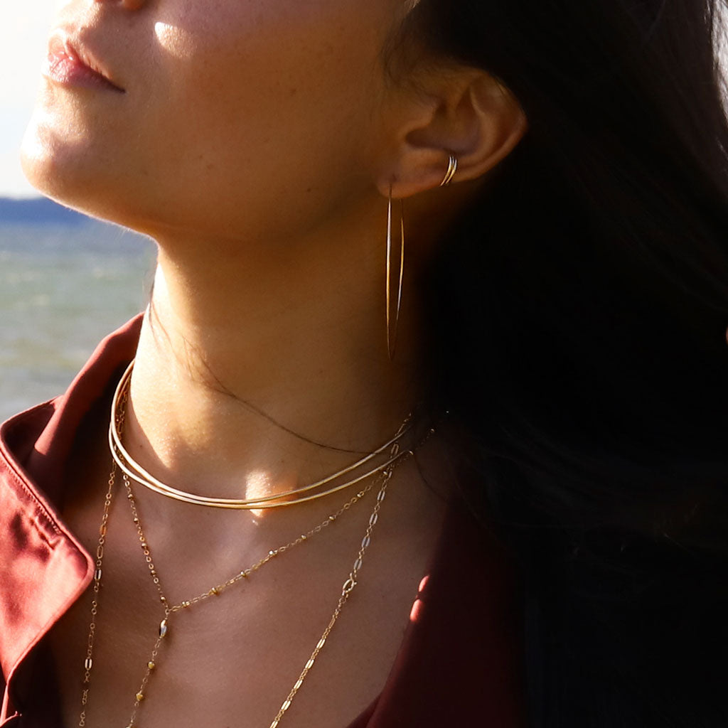 brunette on a red wine shirt under sunlight wearing two stacked 14k gold filled cartilage hoop earrings