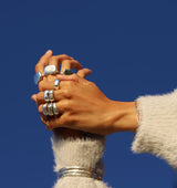 Woman's hands wearing big silver rings silver link bracelet and three thick bracelets