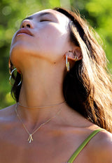 young woman wearing irregularly shaped gold hoop earring with her head tilted back