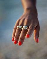 multiple chunky organically shaped gold rings on brown hand with bright red nails