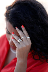 stacked chunky sterling silver rings on girl in bright red shirt with bright red nails