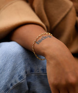 gold chain bracelet against lucky tattoo wrist