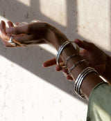 Woman wearing big silver rings, link bracelets, thick silver bracelets, and a green blouse