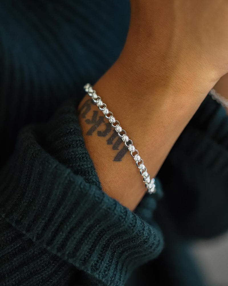silver rolo chain bracelet closeup with wrist tattoo and green sweater