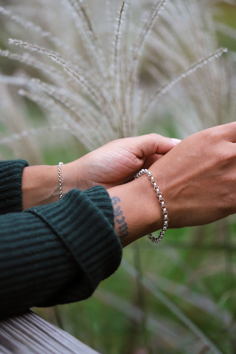 wrists with silver chain bracelets and pompas grass backgroung
