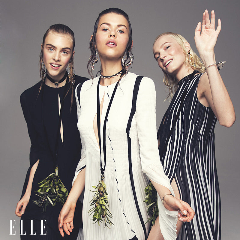 3 elle models in black and white dresses wearing multiple pieces of jewelry on ears neck and wrists 
