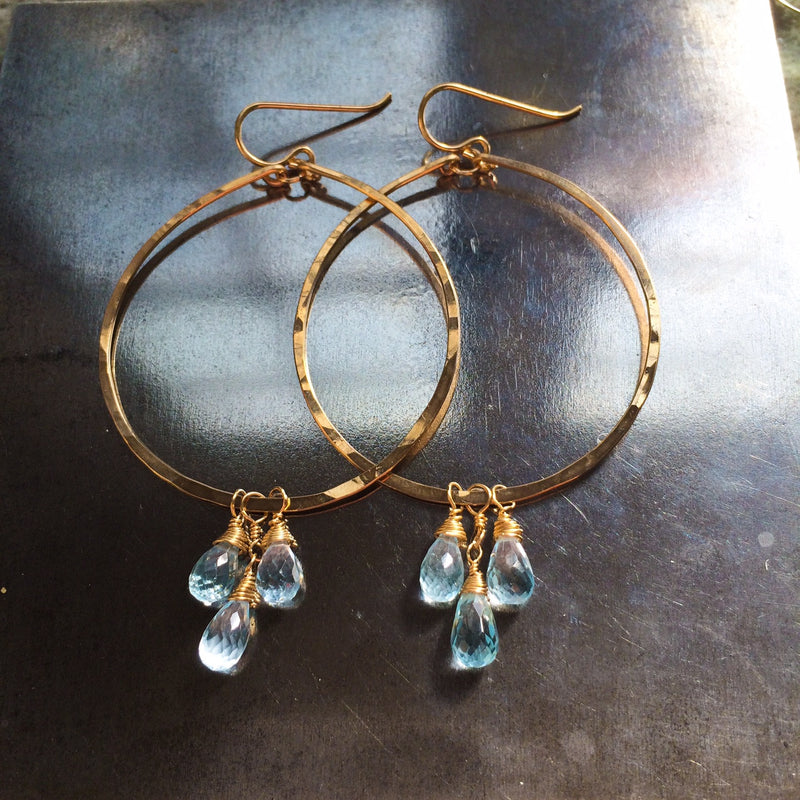 blue topaz and 14k gold filled hammered hoop earrings on steel hammering block