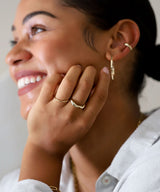 girl smiling with hand against face wearing gold rings and hoops