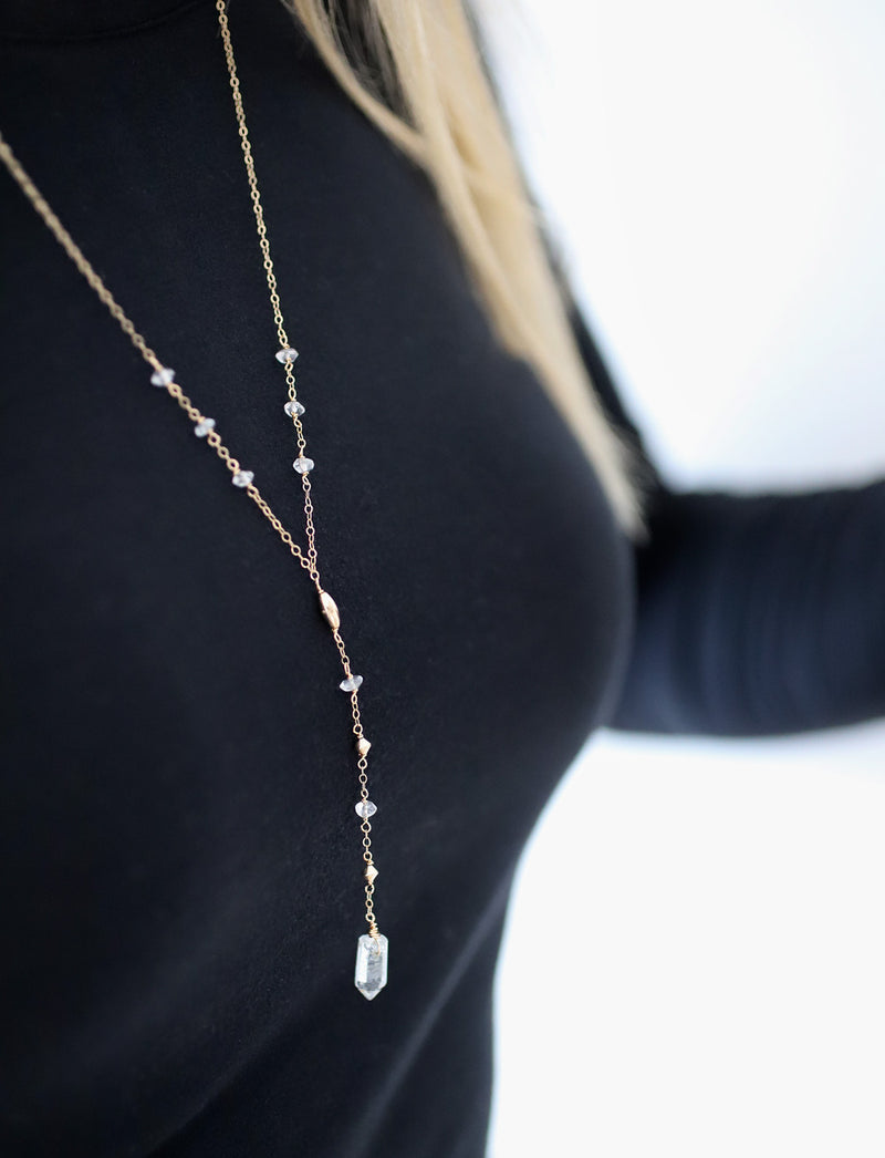 breast closeup of a blond woman on a black long sleeve wearing a 14k gold filled aquamarine y gemstone necklace