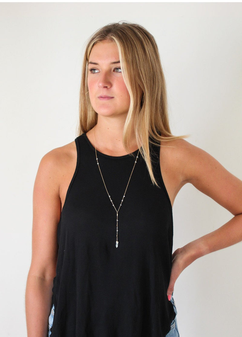blond woman looking to the side on a black tshirt wearing a 14k gold filled aquamarine y gemstone necklace