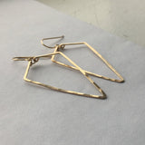 14k gold filled arrowhead hoop earrings laying on a grey surface 