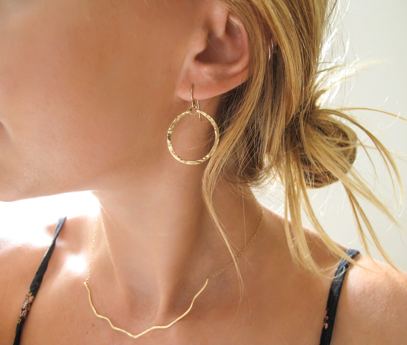 blond woman wearing 14k gold filled baby hoop earrings reflecting light