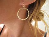 blond woman ear closeup wearing 14k gold filled baby hoop earrings reflecting light