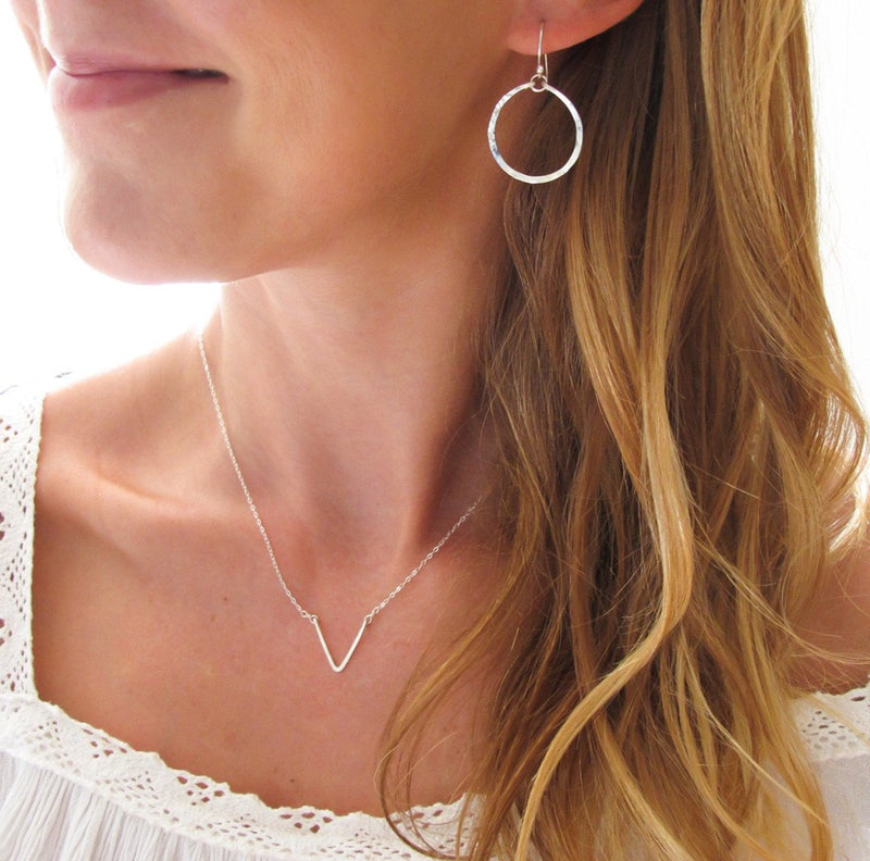 blond woman on a white top wearing sterling silver baby hoop earrings reflecting light