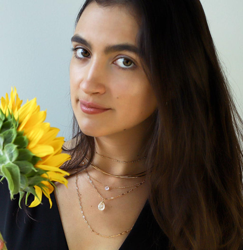 girl with layered moonstone necklaces holding sunflower
