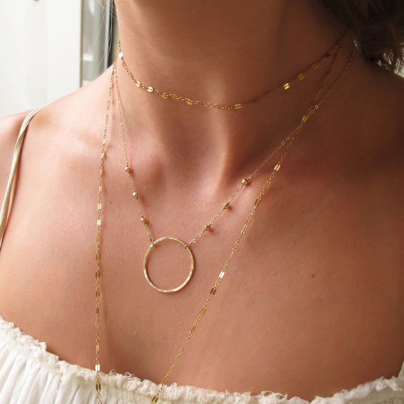 blond woman on a white top wearing a 14k gold filled xl unity beaded necklace with a gold circle pendant