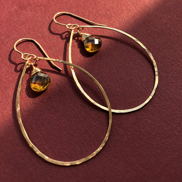 14k gold filled beer quartz teardrop gemstone earrings simultaneously under sun and shade on a red wine surface