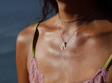 tan woman neck close-up wearing 14k gold filled blades pendant necklace and a 14k gold filled xl scenic route necklace