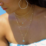 girl with delicate layered gold and blue gemstone necklaces.