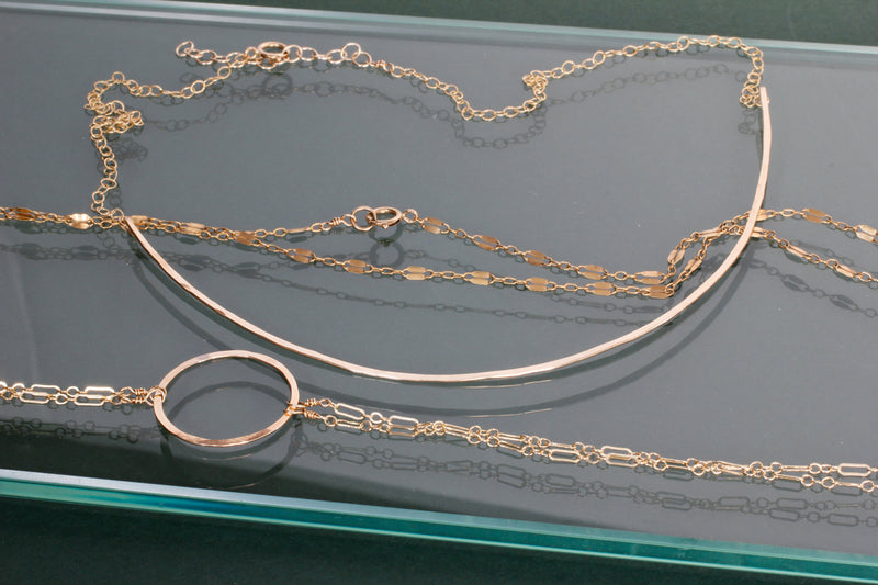 delicate gold necklaces on a table by delia langan jewelry
