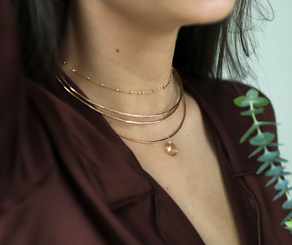 woman neck close up wearing 3 halo 14k gold filled collars with a champagne quartz gemstone and a ball chain choker necklace