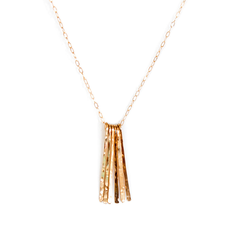 14k gold filled different strokes fringe pendant necklace on a white surface