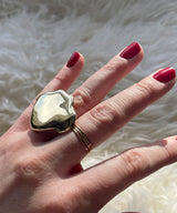 extra large cloud shape ring on hand with red nails against sheepskin