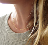 blond woman on a white sweater neck closeup wearing a 14k gold filled coastal route necklace