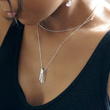 black woman looking down on a black tank wearing a sterling silver different strokes fringe pendant necklace