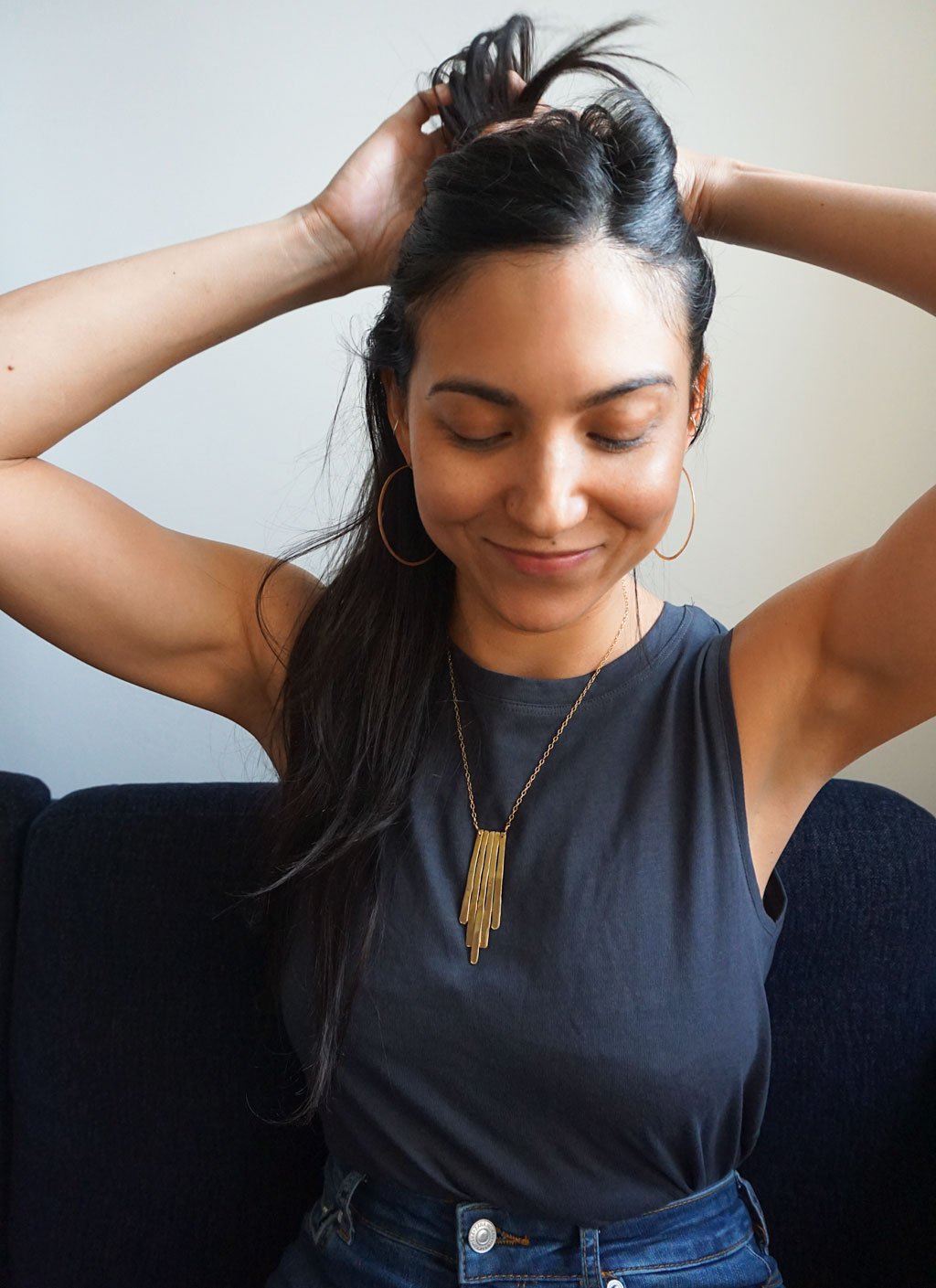 brunette looking down wearing 14k gold filled chain empire pendant necklace and 14k gold filled horizon endless hoop earrings 
