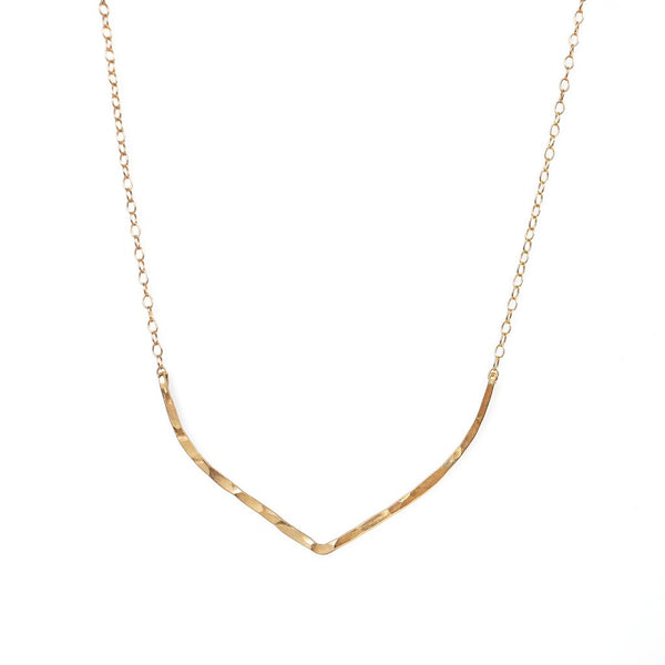 14k gold filled flight necklace on a white surface 