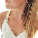 blond woman neck closeup wearing a white top with a 14k gold filled flight necklace