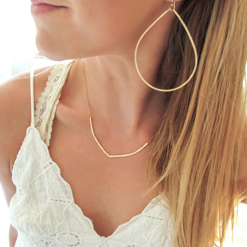 with with large teardrop hoops and gold necklace