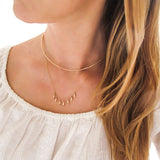 blond woman on a white blouse wearing a 14k gold filled gold grain necklace