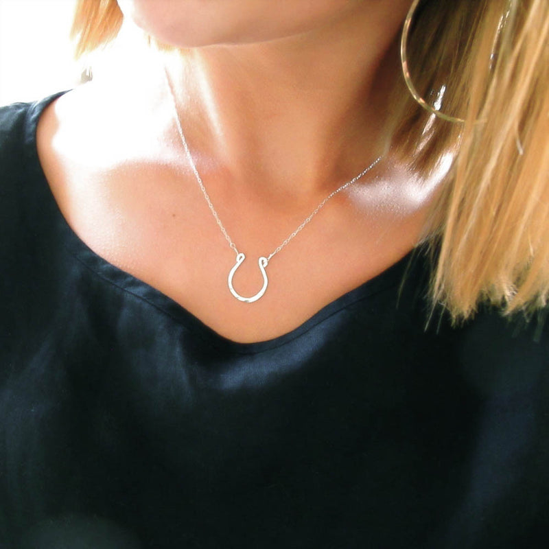 blond woman on a black shirt wearing a sterling silver good luck horseshoe necklace