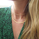 blond woman on a green jumpsuit wearing a 14k gold fill xl scenic route necklace and two 14k gold fill halo collars