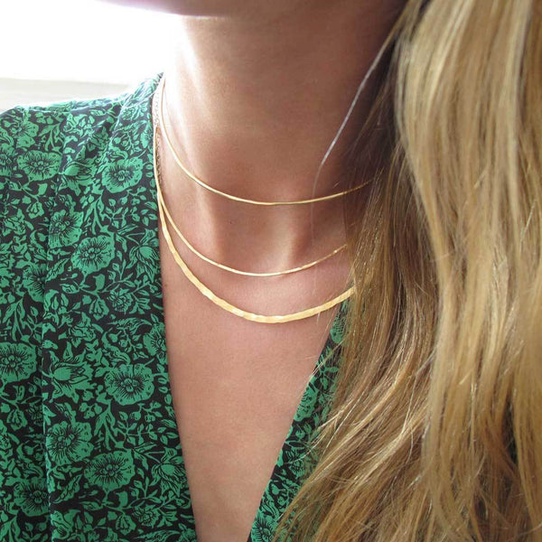 neck closeup of a blond woman on a green jumpsuit wearing a 14k gold filled crescent collar necklace 