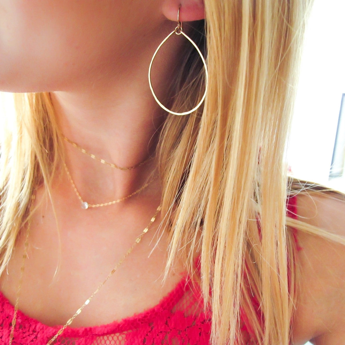 blond woman on a fuchsia top wearing 14k gold filled hoops for nuns hoop earrings